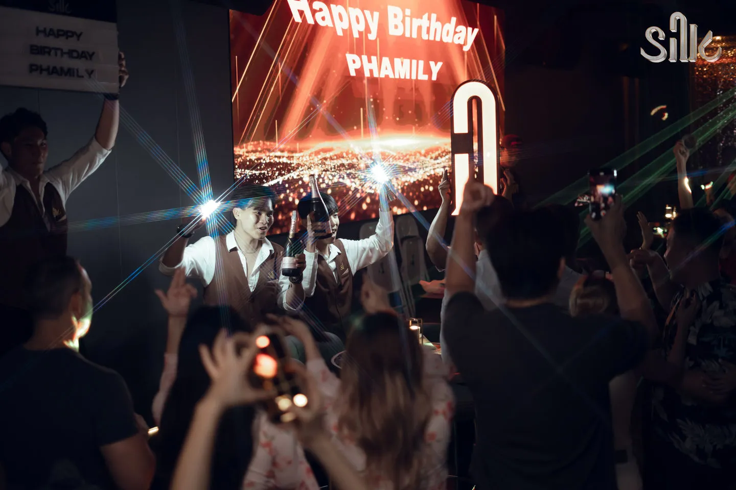 Birthday celebration with LED screen display, sparklers and staff presenting champagne bottles